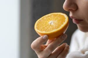 image of a woman smelling an orange